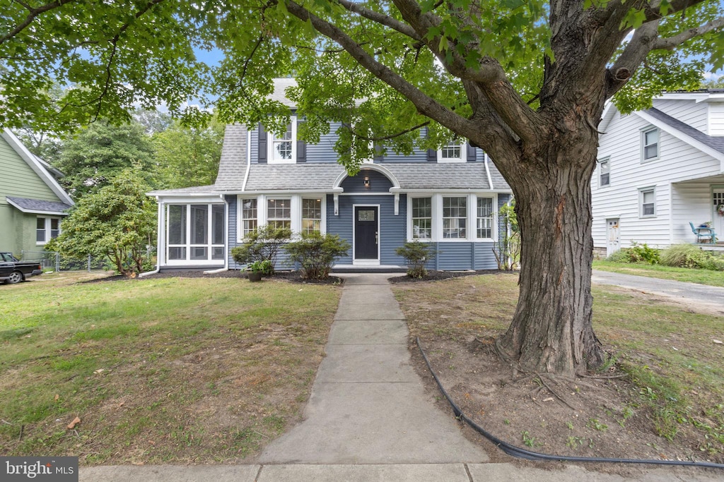 view of front of home featuring a front yard and a sunroom