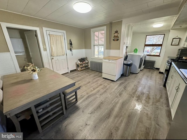 kitchen featuring white cabinets, washer / dryer, light wood-type flooring, and a wealth of natural light