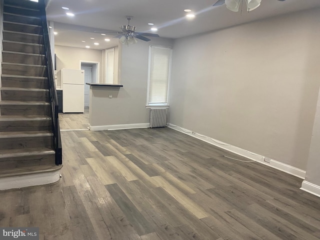 unfurnished living room featuring radiator heating unit, ceiling fan, and wood-type flooring