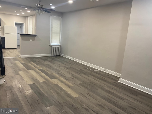 unfurnished living room featuring radiator, ceiling fan, and dark wood-type flooring