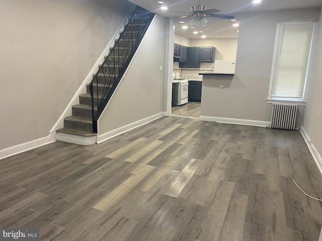 unfurnished living room featuring ceiling fan, dark hardwood / wood-style flooring, and radiator heating unit