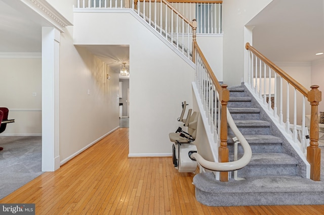 stairs featuring hardwood / wood-style flooring, a towering ceiling, and crown molding