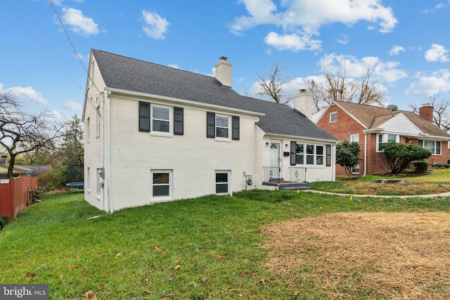 rear view of property featuring a lawn and a trampoline