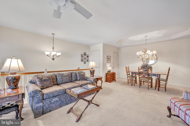 living room with a tray ceiling, light carpet, and ceiling fan with notable chandelier