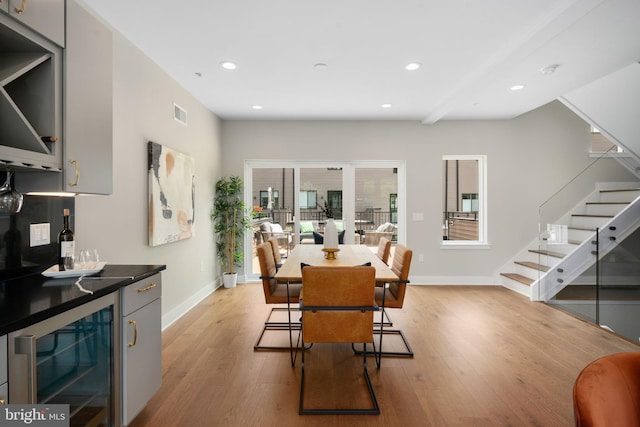 dining area featuring wine cooler, indoor bar, and light wood-type flooring