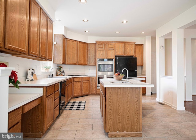 kitchen featuring light tile patterned floors, sink, a kitchen island with sink, and black appliances