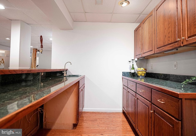 bar with a drop ceiling, sink, and light hardwood / wood-style flooring