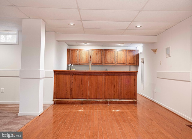 bar featuring a paneled ceiling and light hardwood / wood-style flooring