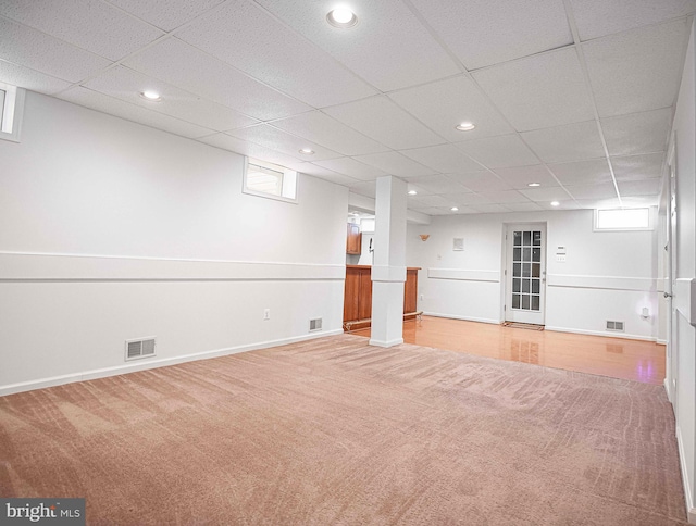 basement featuring a drop ceiling, a healthy amount of sunlight, and light carpet