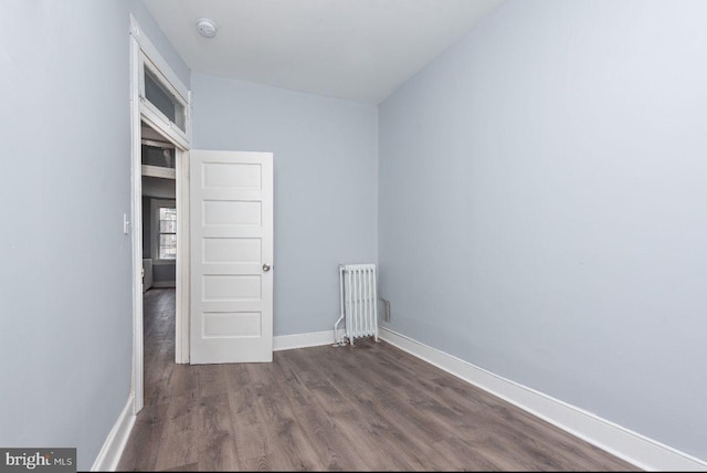 unfurnished room featuring radiator heating unit, vaulted ceiling, and dark wood-type flooring