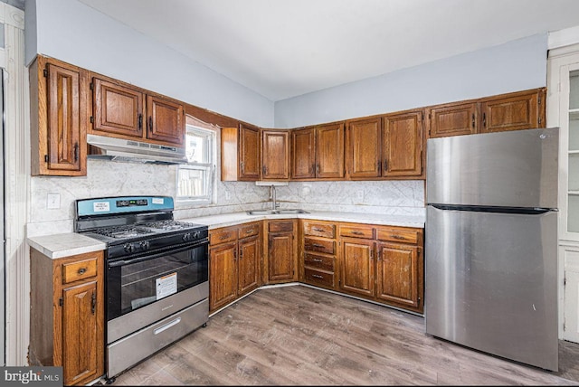 kitchen with backsplash, stainless steel appliances, hardwood / wood-style flooring, and sink