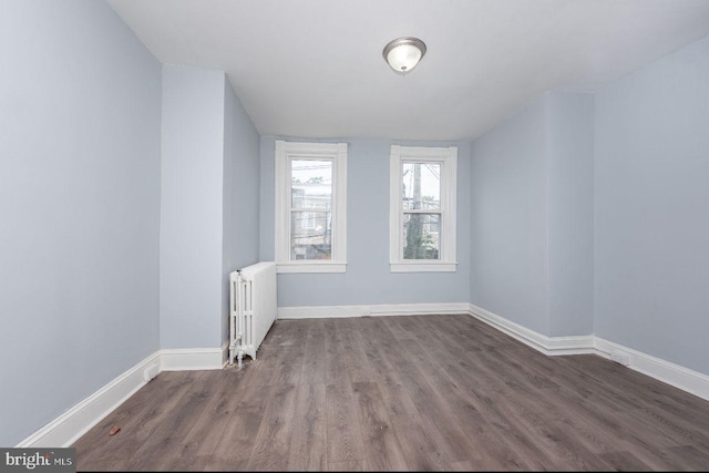 spare room with dark hardwood / wood-style floors and radiator heating unit