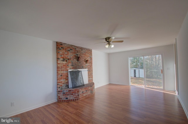 unfurnished living room with ceiling fan, wood-type flooring, and a brick fireplace