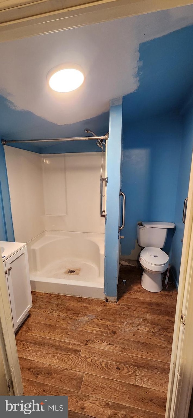 bathroom featuring hardwood / wood-style flooring, toilet, and a shower