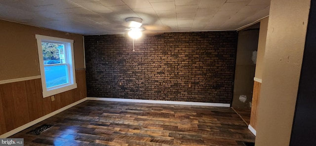 unfurnished room with dark wood-type flooring, wooden walls, and brick wall