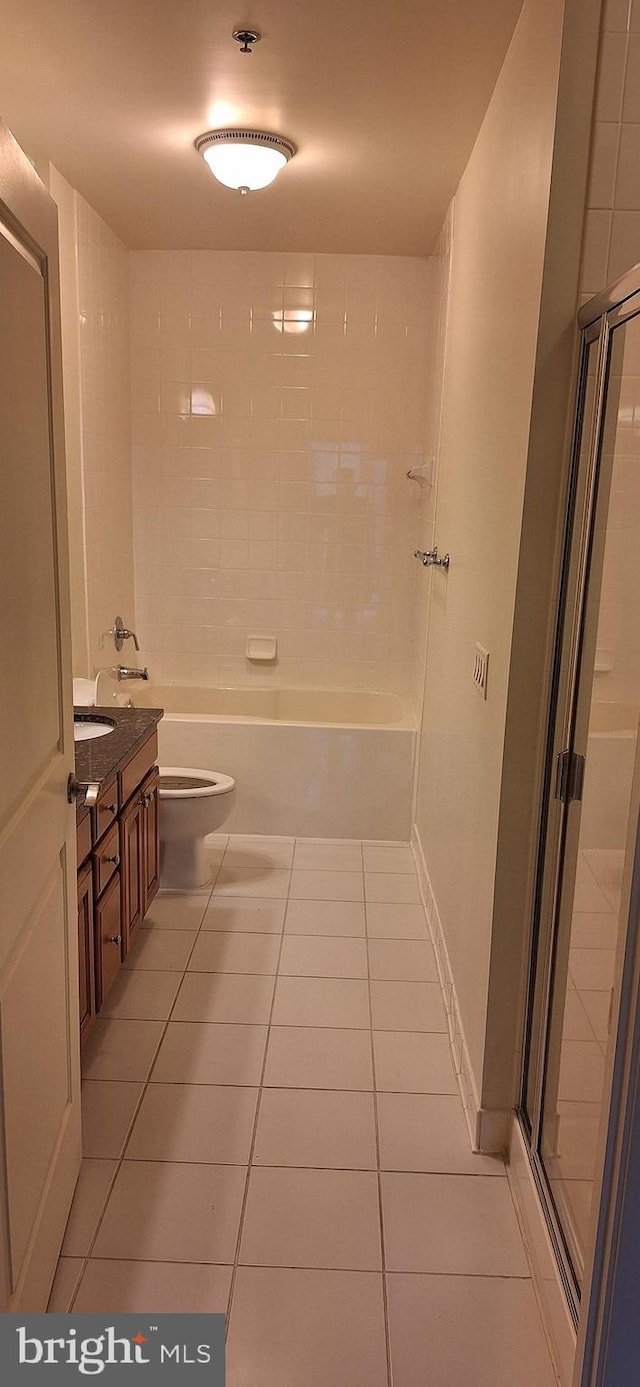 bathroom with a tile shower, tile patterned flooring, vanity, and toilet