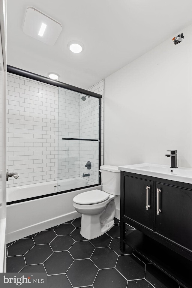 full bathroom with shower / bath combination with glass door, tile patterned flooring, vanity, and toilet