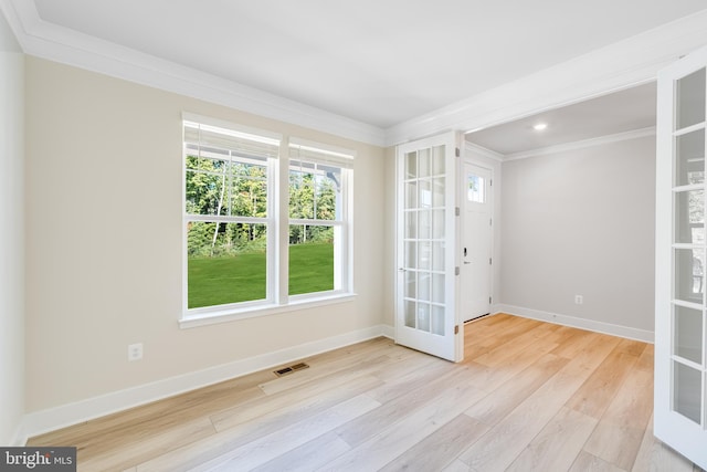 empty room with light wood-type flooring, ornamental molding, and french doors