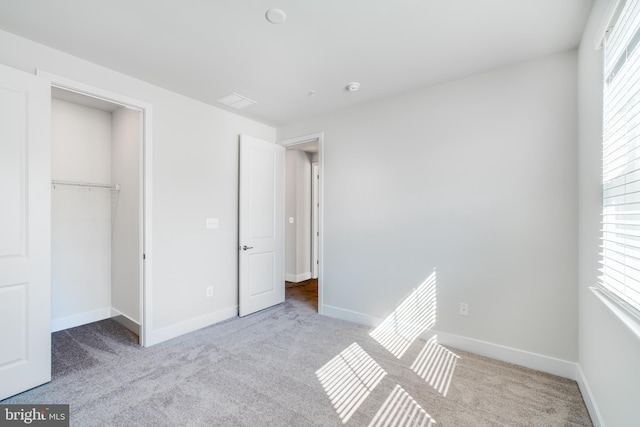 unfurnished bedroom with light colored carpet and a closet