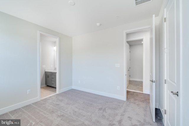 unfurnished bedroom with light colored carpet and ensuite bath