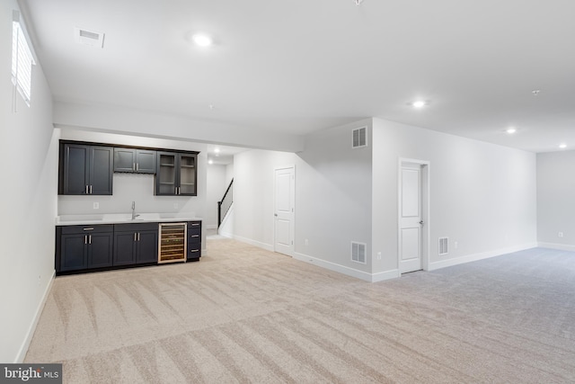 unfurnished living room featuring light colored carpet, wine cooler, and wet bar