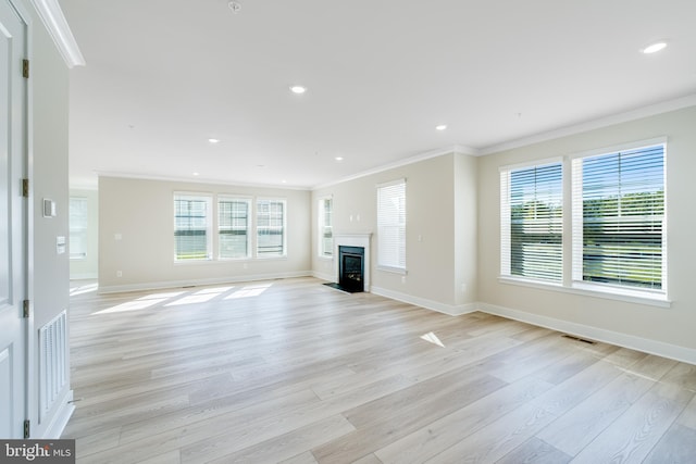 unfurnished living room with plenty of natural light, light wood-type flooring, and crown molding