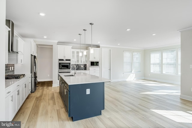 kitchen featuring decorative backsplash, stainless steel appliances, decorative light fixtures, white cabinetry, and an island with sink