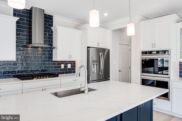 kitchen featuring wall chimney range hood, sink, hanging light fixtures, tasteful backsplash, and stainless steel appliances