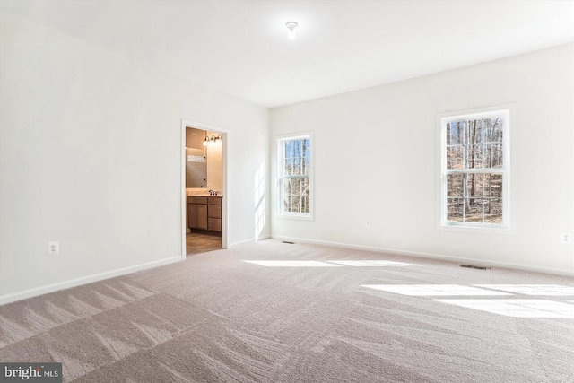 unfurnished bedroom featuring ensuite bathroom and light colored carpet