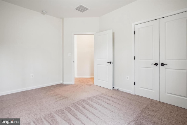 unfurnished bedroom featuring light carpet and a closet