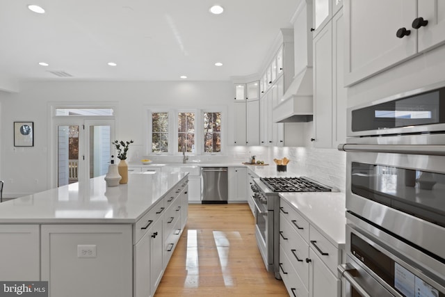 kitchen featuring light hardwood / wood-style floors, a kitchen island, white cabinetry, and stainless steel appliances