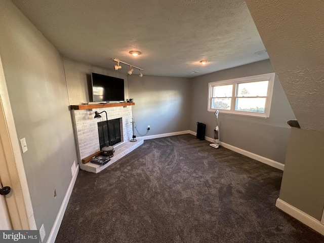 unfurnished living room featuring a fireplace, a textured ceiling, and dark carpet