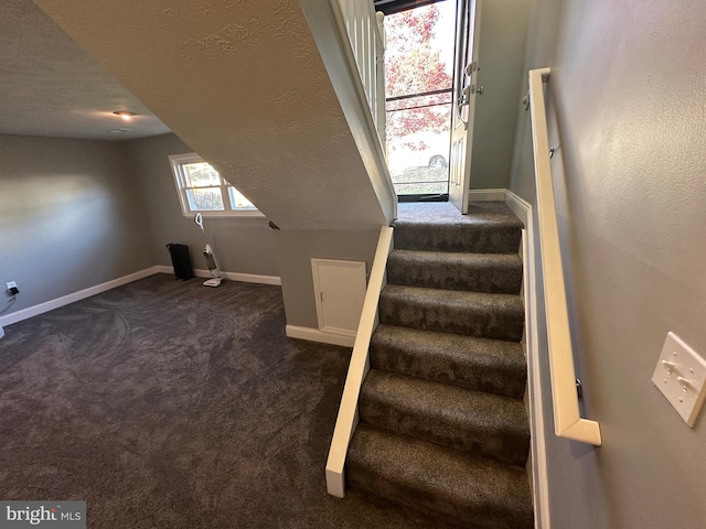 stairway with carpet floors and a textured ceiling