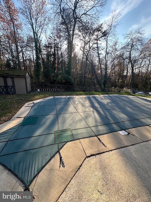 view of pool featuring a patio and a storage shed