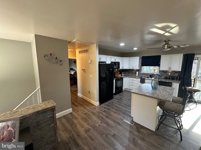 kitchen featuring white cabinetry, dark hardwood / wood-style floors, a breakfast bar, a kitchen island, and black appliances