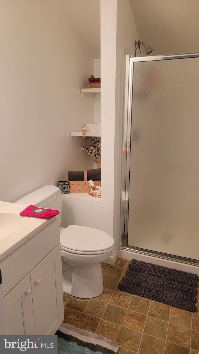 full bath featuring toilet, a stall shower, stone finish floor, and vanity