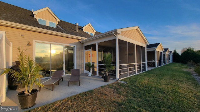 rear view of house with a patio, a lawn, and a sunroom