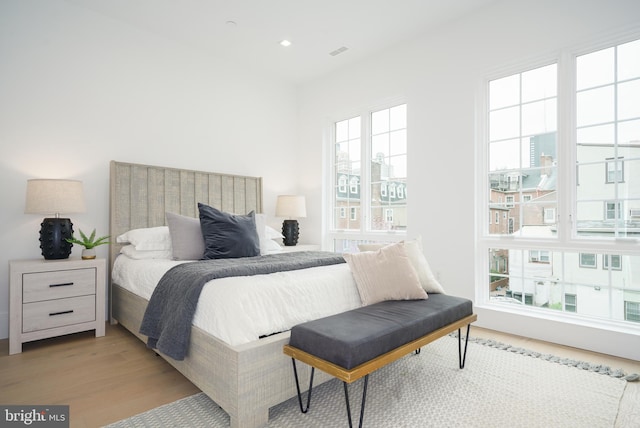 bedroom with multiple windows and light hardwood / wood-style flooring