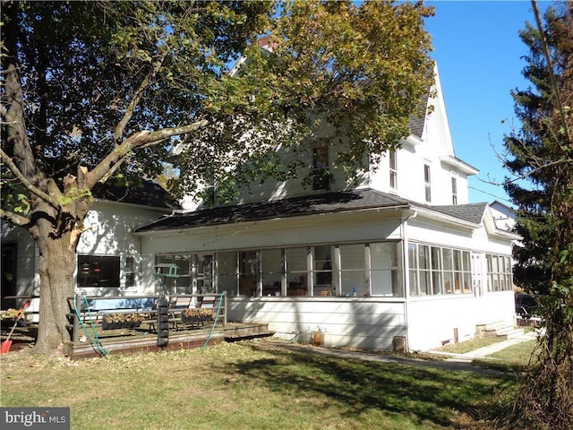 back of property featuring a sunroom and a yard