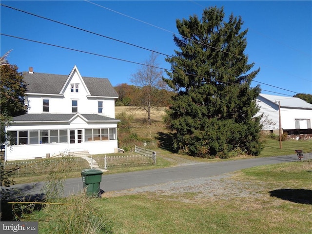 view of front facade with a sunroom and a front yard