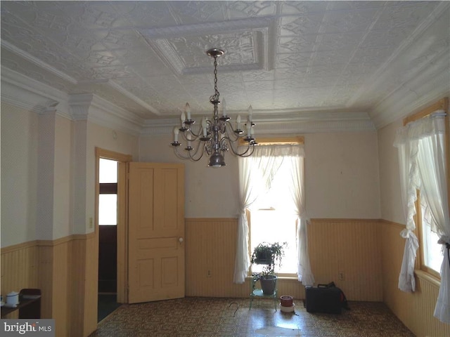 spare room with a healthy amount of sunlight, ornamental molding, and an inviting chandelier