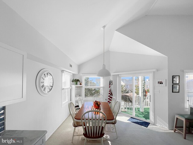 carpeted dining area with lofted ceiling