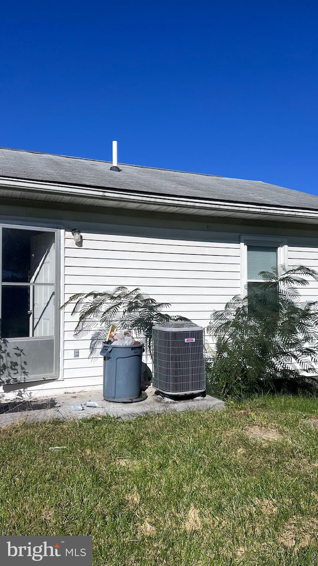 view of side of property featuring a yard and central AC unit