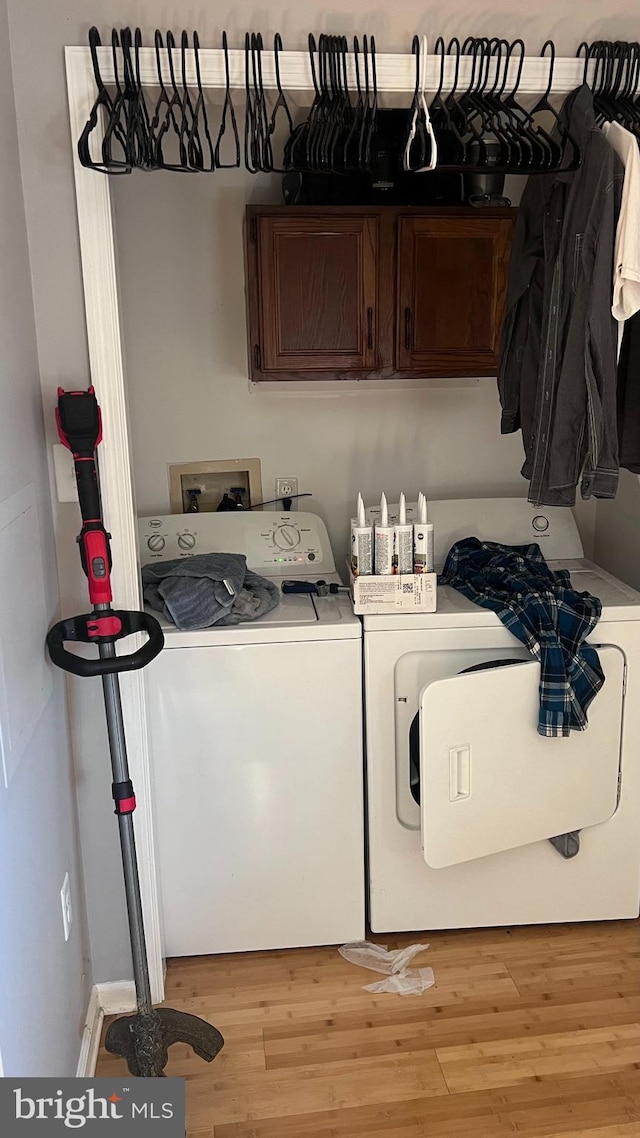 washroom featuring cabinets, light hardwood / wood-style floors, and washer and clothes dryer