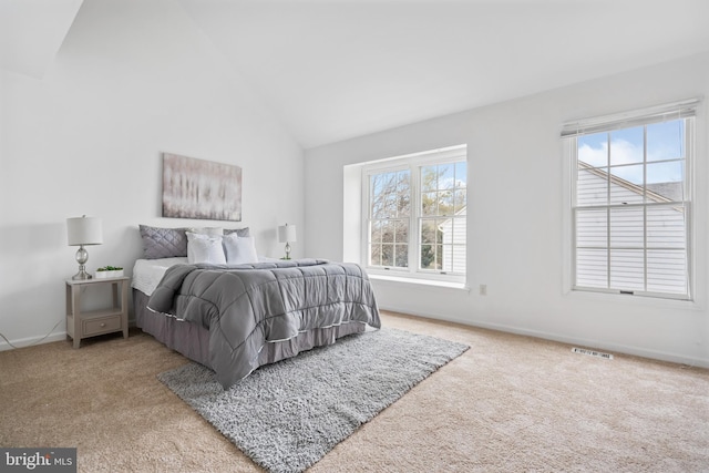 carpeted bedroom with visible vents, vaulted ceiling, and baseboards