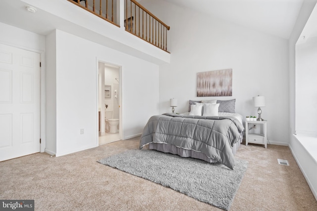 carpeted bedroom with baseboards, visible vents, high vaulted ceiling, and ensuite bathroom