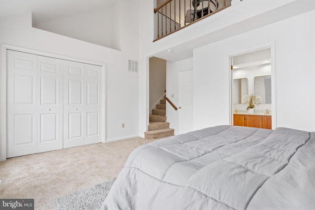 bedroom with visible vents, ensuite bathroom, carpet, a high ceiling, and a closet