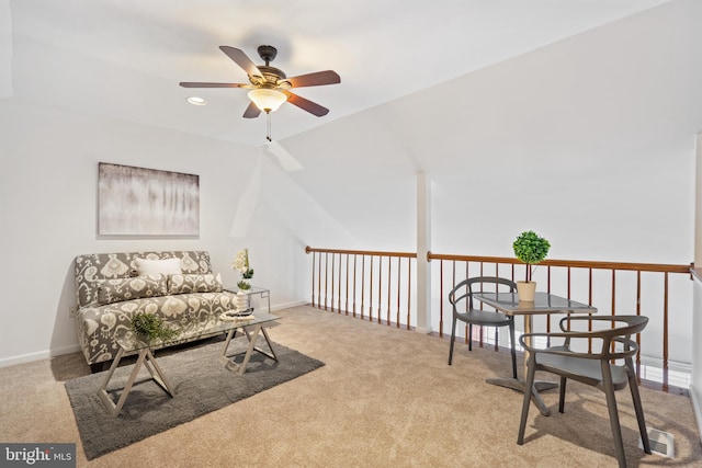 living area featuring light colored carpet, ceiling fan, and baseboards