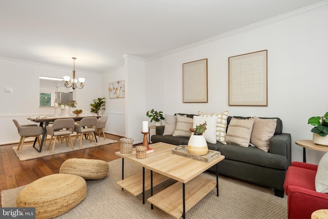 living area featuring baseboards, a chandelier, wood finished floors, and ornamental molding