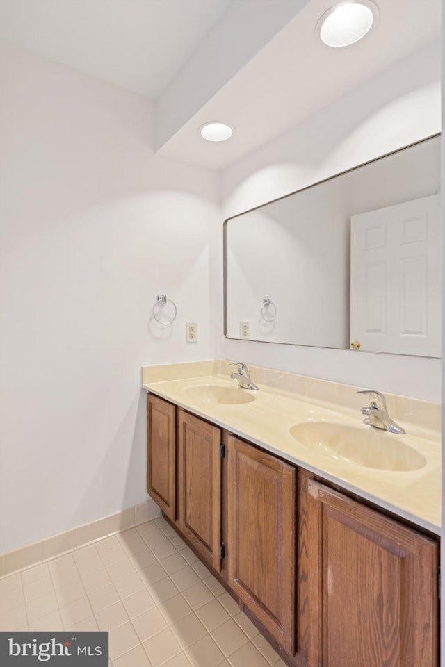 bathroom featuring tile patterned floors, a sink, baseboards, and double vanity